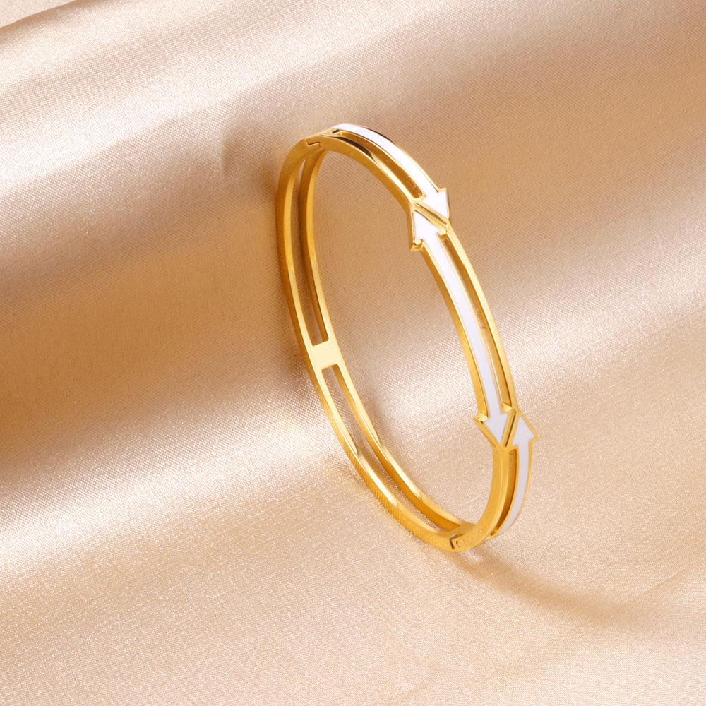 gold colored hard bracelet with directional arrows